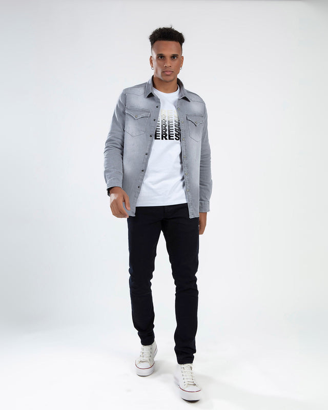 Man wearing Tom Grey Washed Denim Shirt by Carbon over a white graphic tee and black pants.