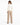 A woman in a fitted cream jacket and beige wide-leg pants stands with her back to the camera, showcasing a sleek silh...