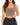 A woman wearing a cropped, ribbed top in a neutral brown shade, paired with high-waisted black jeans.