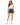 A woman stands confidently in a fitted ribbed crop top and high-waisted denim shorts, paired with white sneakers.