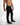 Side view of Mason slim straight black streetwear jeans with subtle knee distressing on a model.