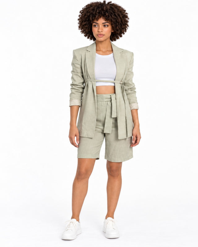 A model showcases a light green blazer and matching shorts, paired with a white crop top and white sneakers.