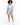 A woman with curly hair wears a light blue blazer and matching shorts, paired with a white crop top and sneakers.