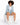 A woman with curly hair sits on a white cube, wearing a light blue suit and white sneakers, showcasing stylish shorts.