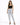 A woman stands confidently in light-wash ripped jeans and a black crop top, paired with black heels.
