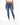 A model wearing fitted blue jeans paired with a white cropped top and white sneakers, standing against a plain backgr...