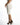 Side view of Eve White Pencil Skirt, a high-waisted midi skirt with a curve-hugging fit and gold hardware detail.