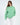 Model wearing the Eve Top, an oversized light green crewneck sweatshirt with 'More and Less' embroidered on the chest.