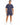 A man stands confidently in a navy outfit featuring casual shorts and a matching t-shirt, paired with white sneakers.