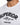 Close-up of a white shirt featuring bold black embroidered text and a round neckline.