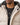 A close-up of a beige coat with a fur-lined hood, worn over a black t-shirt featuring a circular graphic.