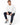 A man sits on a white stool wearing a textured white sweatshirt, navy pants, and stylish sneakers.