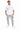 A man stands wearing a white graphic t-shirt and light gray cargo pants, paired with white sneakers.