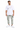 A man stands wearing a white graphic t-shirt, light green cargo pants, and white sneakers with black accents.