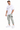 A man stands wearing a white graphic t-shirt, light green cargo pants, and white sneakers.