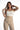 Model wearing the white Emmie Strapless Bustier Top with a structured bodice and tan pleated trousers.