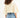 Back view of a woman in a clay-colored one shoulder cropped sweatshirt with wide sleeves and blue denim jeans.