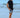 Man on beach wearing Carter patterned swim trunks and black t-shirt, showing trendy summer swimwear style.