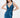 A model poses in a deep blue satin dress with a plunging neckline and a thigh-high slit, showcasing elegant draping.