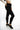 Side view of model in Blakely black high-waisted skinny jeans with raw hems and black platform sneakers.