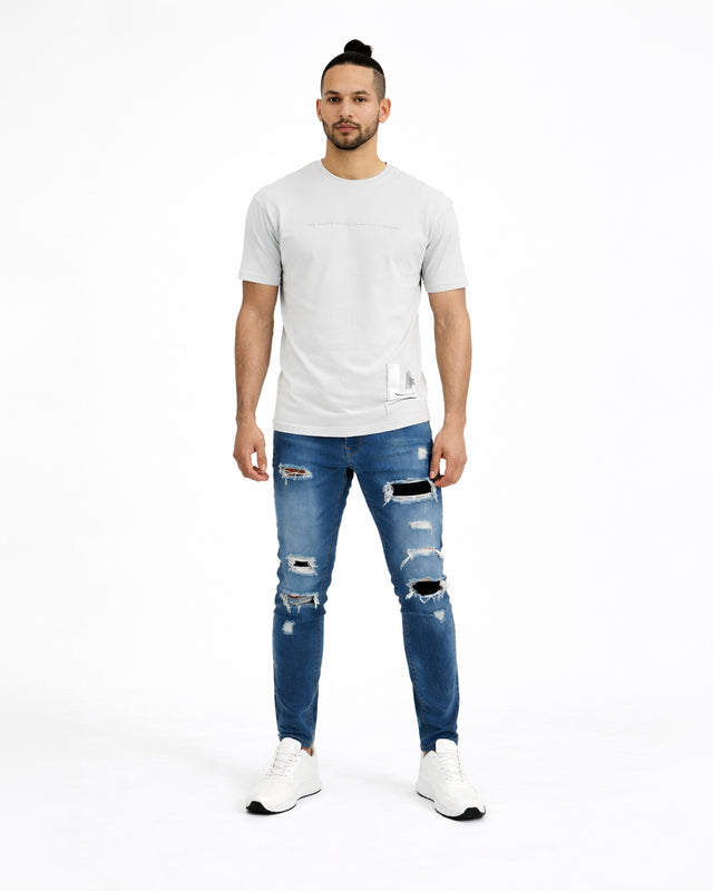 Aaron Blue Washed Jeans for men featuring distressed ripped details and patchwork on a studio model.