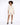 A model poses in a light beige button-up shirt and matching shorts, complemented by black heeled sandals.