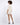 A model with curly hair wears a light-colored, short-sleeve top and matching shorts, paired with black heels.