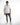 A model stands confidently in a fitted white shirt with black accents, paired with distressed gray jeans and white sn...