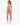 A woman in a backless pink velvet outfit with a chain detail, paired with white sneakers, poses from behind.