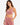 A woman models a sleeveless, cowl-neck crop top in pink fabric, paired with matching pants.