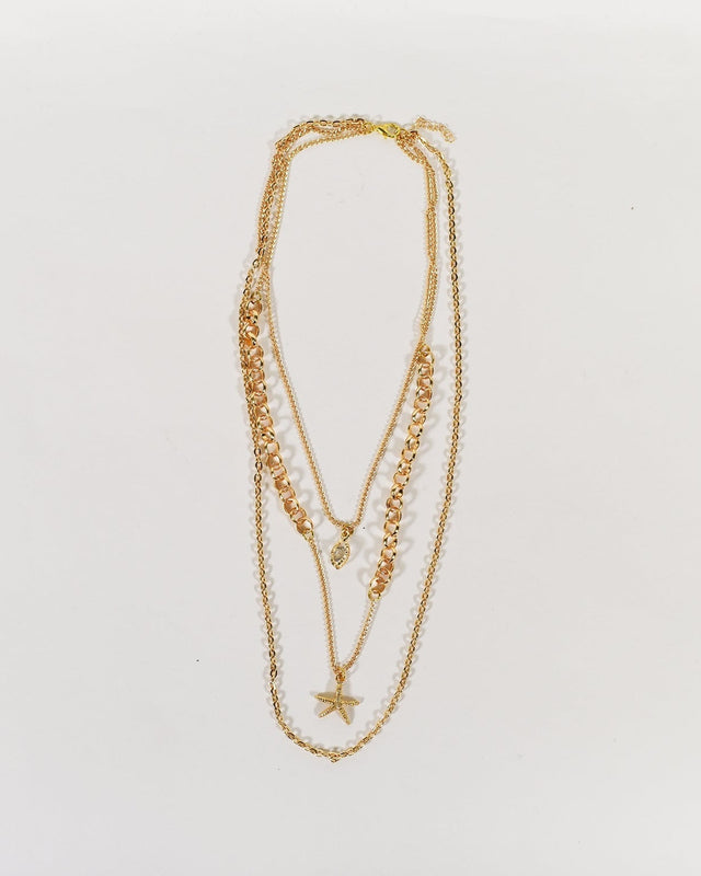 Golden Glow Minimalist layered necklace featuring a gold curb chain, starfish charm, and gemstone on a white background.