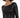 A close-up of a woman wearing a fitted black sequin dress with long sleeves and a boat neckline.