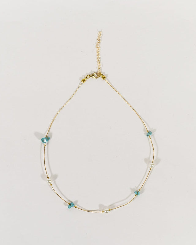Golden minimalist chain necklace featuring raw turquoise stones and white pearls on a thin wire with lobster clasp.