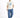 A man wearing a cream graphic t-shirt with blue text and relaxed blue patterned jeans, paired with white sneakers.