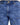 Close-up of blue patterned denim jeans featuring a button closure and angled pockets with decorative stitching.