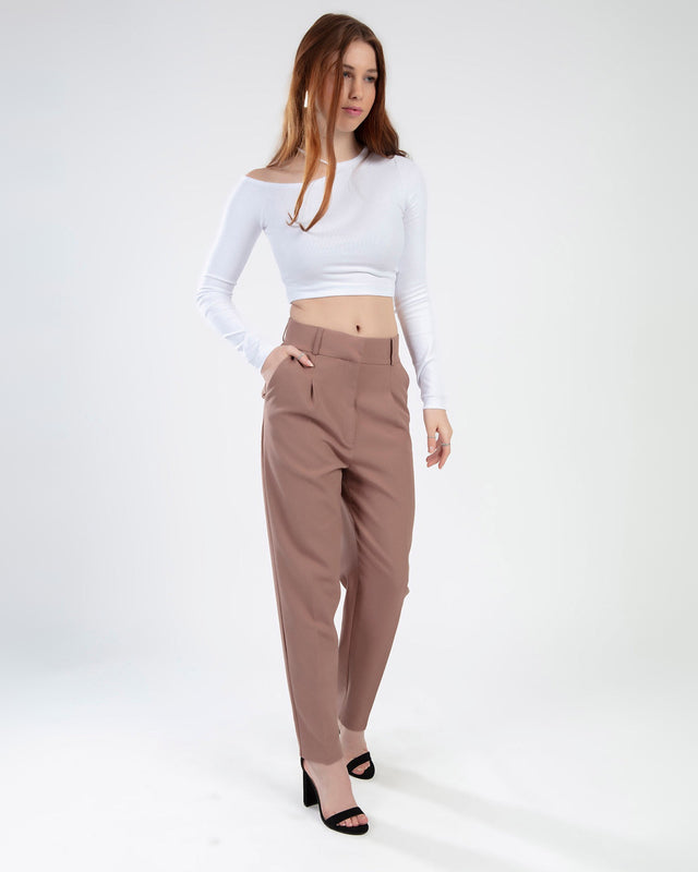 Model wearing the Adriana White Off-Shoulder Long Sleeve Crop Top with high-waisted brown trousers and black heels.