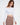 Model wears the Adriana off-shoulder long sleeve crop top in white with a unique strap neckline and brown trousers.