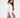 Back view of a white Adriana off-shoulder long sleeve crop top paired with brown high-waisted trousers.