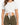 A cropped white top with short sleeves, featuring a front knot detail, paired with olive green high-waisted bottoms.