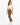 A woman stands in a casual outfit featuring a knotted white crop top and olive green leggings, paired with white snea...