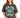 A woman wearing a loose-fitting gray t-shirt featuring a colorful graphic design with "New York" and decorative eleme...
