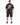 A person wearing a black oversized t-shirt with a graphic design on the back and black shorts, standing from behind.
