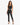 A model poses in a fitted black crop top and matching high-waisted pants with side slits, paired with strappy heels.