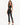 A model poses in a fitted black crop top and high-waisted pants with side slits, paired with strappy heels.