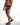 Side view of Niko black and white striped swim trunks with drawstring and matching black slides for a poolside look.