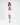 Model wearing the Nina Skirt Set in cream, featuring a cropped blazer and matching mini skirt over a green knit top.