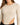 Close-up of a model wearing a ribbed long-sleeve bodysuit with a side cutout in a neutral beige color.