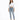 A woman stands confidently in a cropped white long-sleeve shirt and light blue jeans, paired with gray slippers.