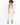 A model poses in a fitted beige bodysuit paired with tailored white pants and black strappy heels.