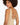 A woman with curly hair poses, showcasing a beige bodysuit with a stylish back design featuring straps.